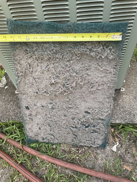 Badly clogged, dirty AC air filter next to a tape measure